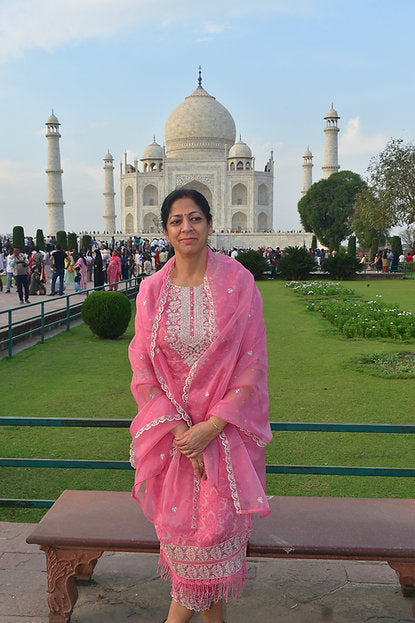 Woman in a pink simple suit standing in front of the Taj Mahal