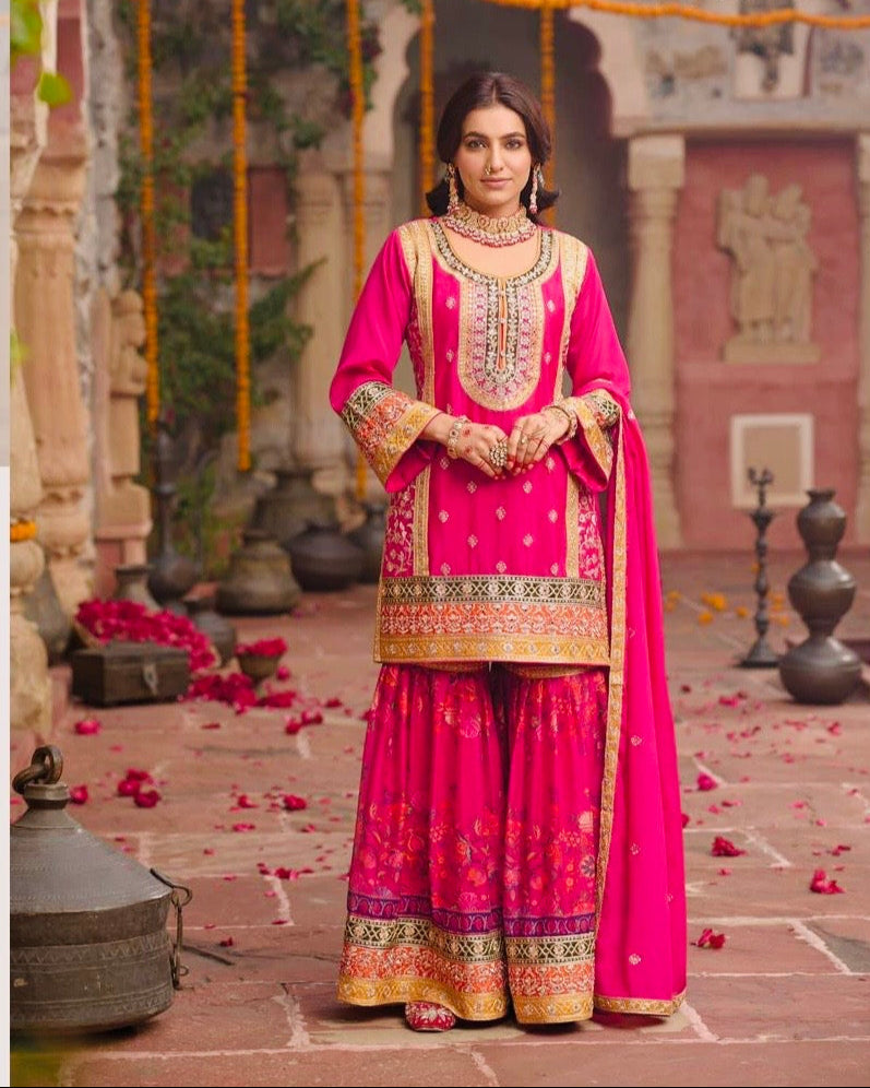 Indian woman wearing a vibrant pink floral printed sharara suit with mirror work and embroidery, styled for festive occasions like Diwali, Rakhi, Teej, and weddings – Meraki Vastram ethnic wear UAE.