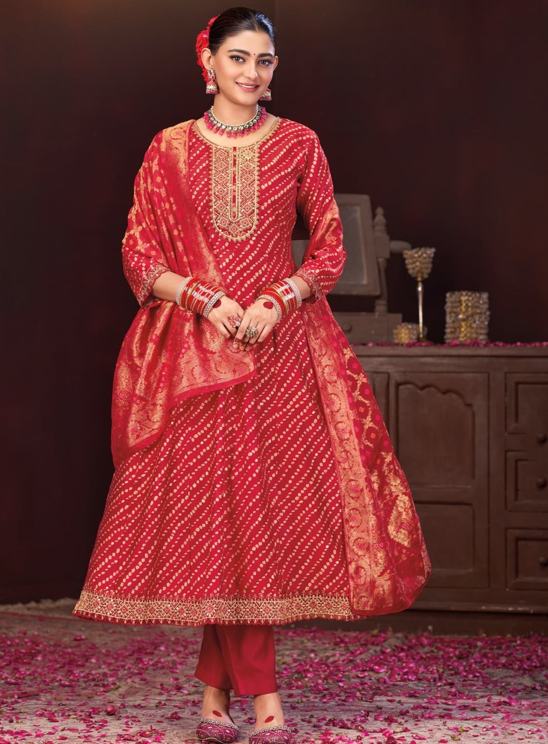 Woman in a red traditional outfit with gold embroidery in a decorated room.