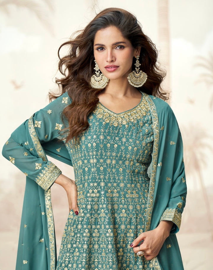 Woman wearing a teal blue Anarkali sharara suit with gold zari embroidery, styled for festive occasions like Diwali, Rakhi, Ganpati, Teej & weddings – ethnic wear by Meraki Vastram UAE.