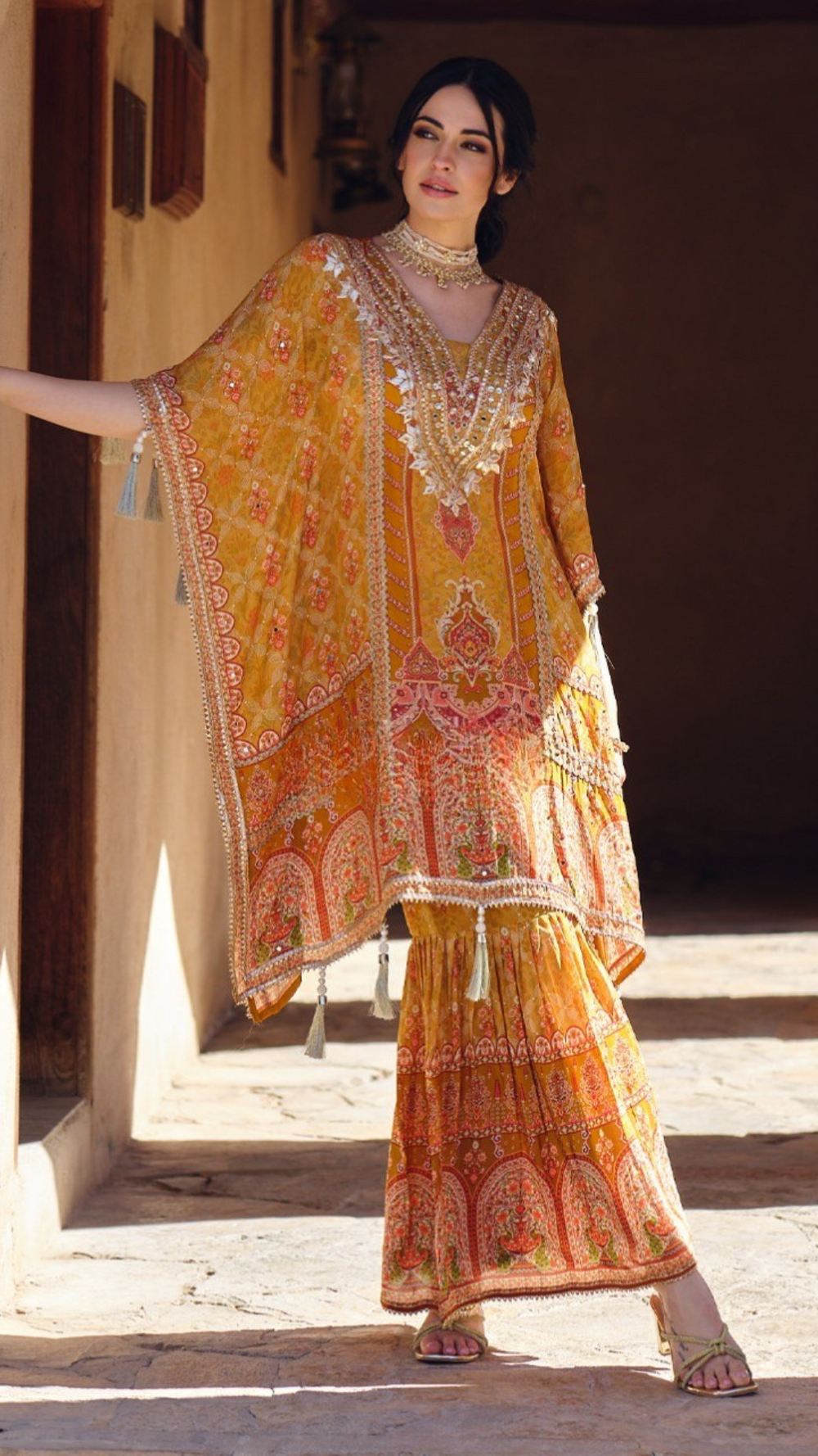 Woman wearing a mustard yellow embroidered kaftan kurta with sharara pants and tassel details – festive outfit for Mehendi, Diwali, Teej and Haldi in UAE by Meraki Vastram.