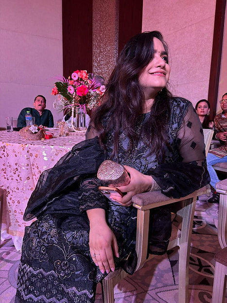 Woman wearing a charcoal and black embroidered suit with sheer net dupatta and flared sleeves – ideal for, evening festive events, and wedding functions in UAE by Meraki Vastram.