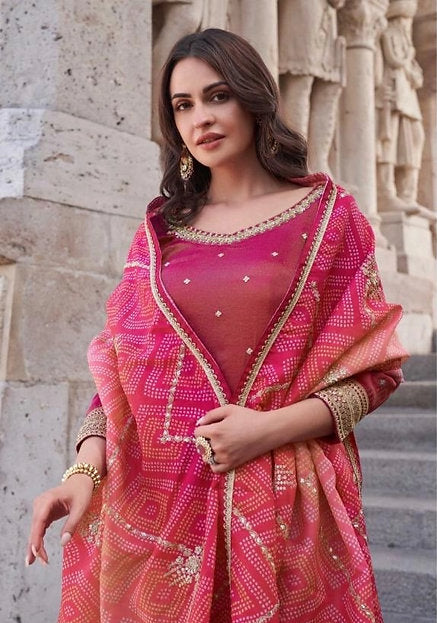 Woman wearing a coral and fuchsia sharara suit with embroidered kurta and pink printed dupatta – ideal for Diwali, Rakhi, Karwachauth, and wedding functions in UAE by Meraki Vastram.
