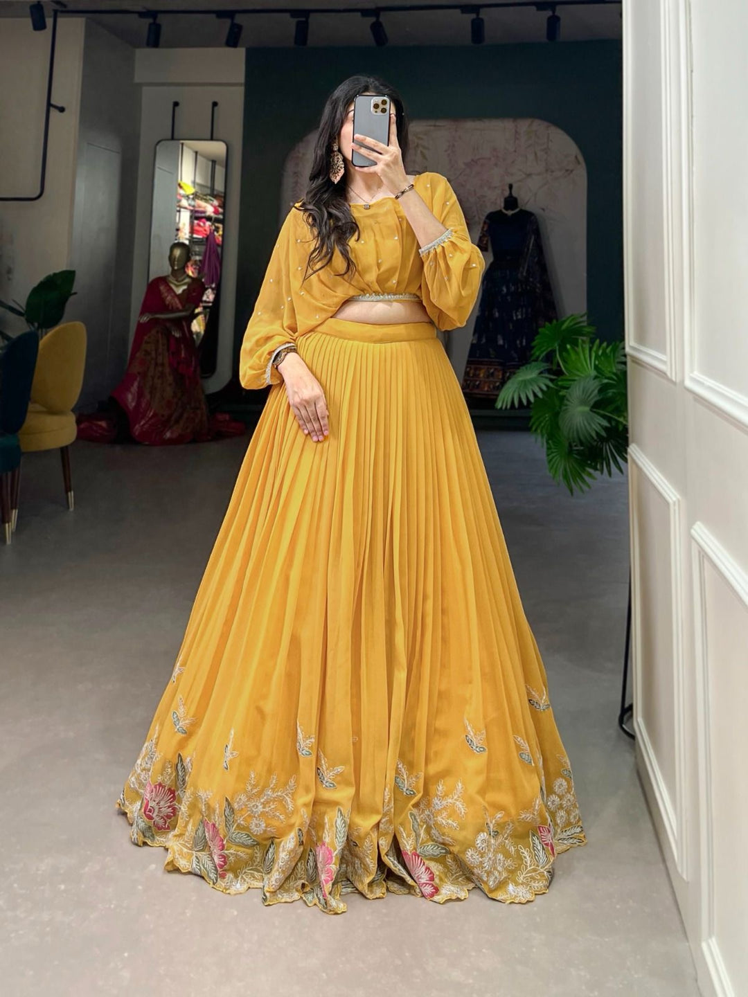 Woman wearing a yellow pleated lehenga with floral embroidery and balloon sleeve blouse, perfect for Haldi, Teej, Diwali, Ganpati and festive celebrations – Meraki Vastram ethnic wear in UAE.
