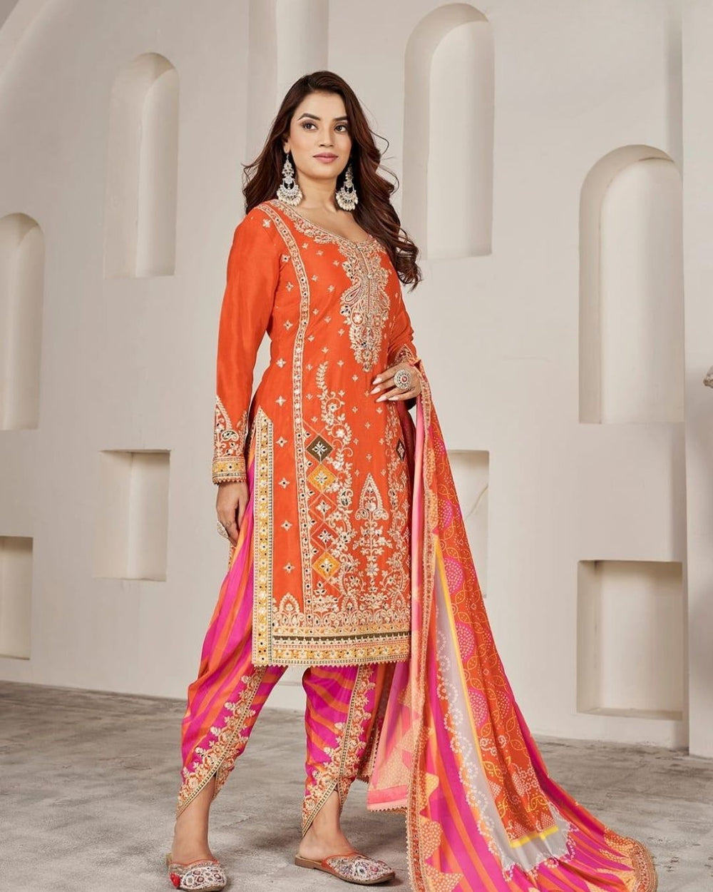 Woman wearing an orange embroidered kurta with pink striped salwar and matching dupatta – festive Punjabi suit for Diwali, Karwachauth, Teej & mehendi functions from Meraki Vastram UAE.