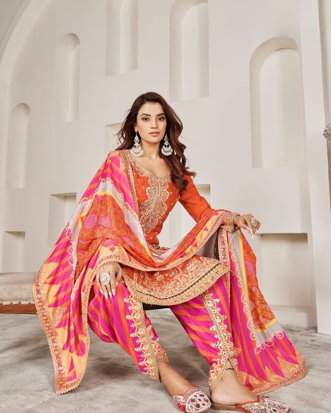 Woman wearing an orange embroidered kurta with pink striped salwar and matching dupatta – festive Punjabi suit for Diwali, Karwachauth, Teej & mehendi functions from Meraki Vastram UAE.