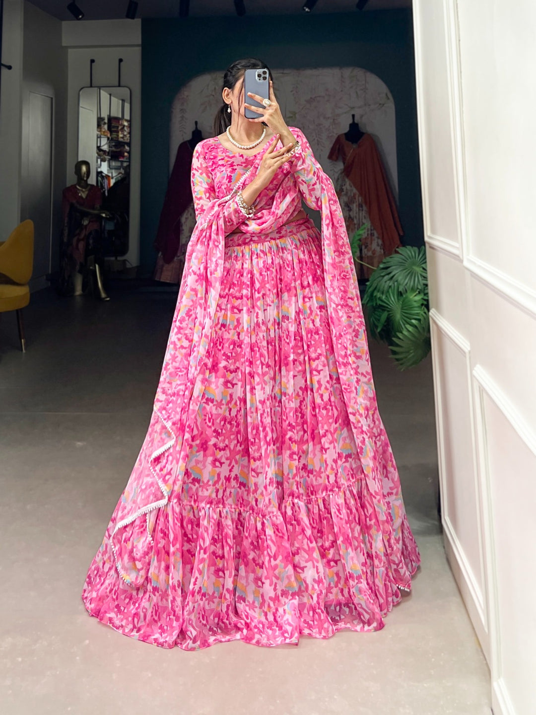 Woman wearing a flowy pink floral printed georgette lehenga with matching blouse and dupatta, perfect for Rakhi, Teej, Ganpati & wedding festivities – Meraki Vastram ethnic wear in UAE.