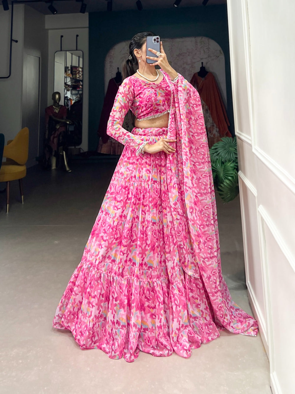 Woman wearing a flowy pink floral printed georgette lehenga with matching blouse and dupatta, perfect for Rakhi, Teej, Ganpati & wedding festivities – Meraki Vastram ethnic wear in UAE.