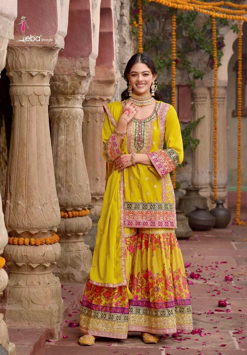 Indian woman wearing a vibrant yellow floral printed sharara suit with mirror work and embroidery, styled for festive occasions like Diwali, Rakhi, Teej, and weddings – Meraki Vastram ethnic wear UAE.